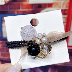 Détail de l'élastique avec perle violette craquelée, perles et nœud en résille
