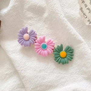 Detailed close-up of colorful daisy flower hair clips on a soft white fabric background