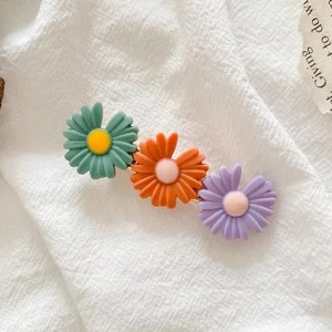 Detail view of colorful daisy flower hair clips on white fabric with a natural light setup