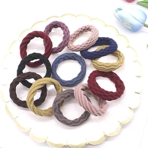 Flat lay of seamless thick elastic hair ties in eleven diverse colors on a ceramic plate