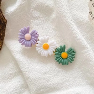 Close-up of triple daisy hair clip with purple white green petals and golden base