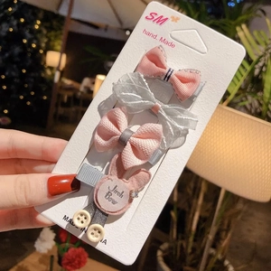Detail of four-piece pink and silver bow hair clip set on a white card display