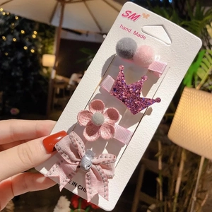 Detail showing 4-piece pink hair clip set with bow, crown, flower and pompom on card