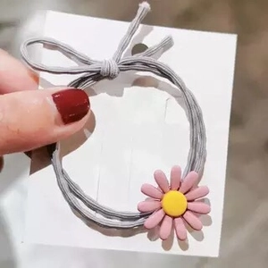 Detail eines grauen elastischen Haargummis mit mattem rosa Gänseblümchen-Resin-Ornament