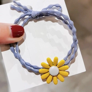 Detail von lila gewelltem Haargummi mit gelbem Gänseblümchen auf weißer Karte