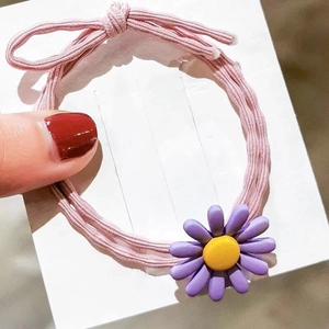 Detail von rosa elastischem Haargummi mit lila Gänseblümchen und kleinem Zierknoten