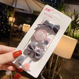 Detailed close-up of a 4-piece cute bow and lollipop hair clip set for girls on display card