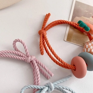 Detail von gewebten elastischen Haargummis in Pink und Orange mit matten geometrischen Perlen