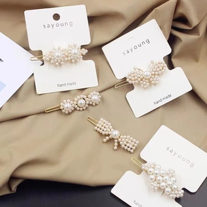 Close-up of handmade pearl hair clips with flower and bow designs on golden metal base