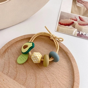 Süßer Avocado-Spiralhaargummi mit karierter Perle auf einem Holztablett Deko
