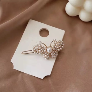 Close-up of golden butterfly hair clip with white pearls on elegant silk background