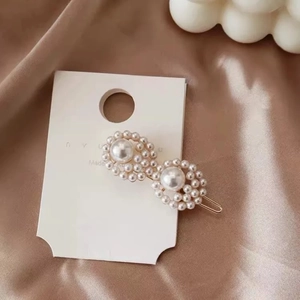 Macro shot of double circle pearl hair clip with gold metal base on champagne satin