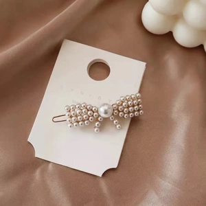 Detail of elegant pearl bow hair clip with tassel on brown satin background