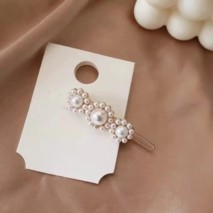 Detailed view of three pearl flower clusters on a gold metal French style hair clip