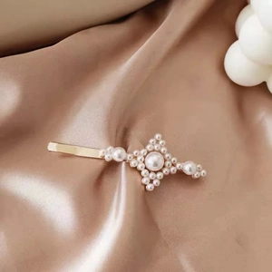 Close-up of elegant gold hair clip with starburst pearl pattern on champagne satin