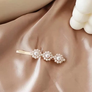 Detail of floral hair clip with pearl clusters on elegant champagne satin fabric
