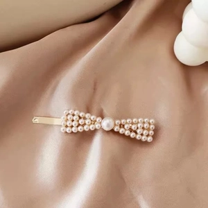 Detail of elegant gold hairpin with ivory pearls on soft silk fabric background