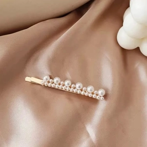 Detail shot of vintage French style pearl hair clip on elegant champagne silk fabric