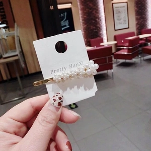 Detailed view of handmade pearl hair clip with gold alloy base on brand display card