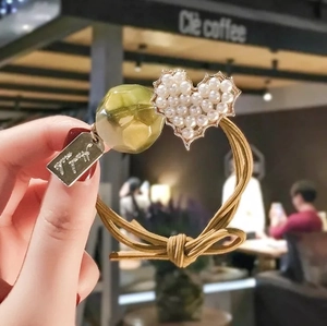 Detail of high-elasticity hair tie featuring pearl heart charm and green resin bead