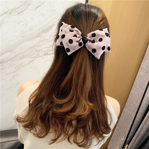 Detailed back view of a soft pink mesh bow hair clip with classic black polka dots