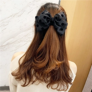 Elegant large black polka dot tulle bow hair clip worn on long wavy hair back view