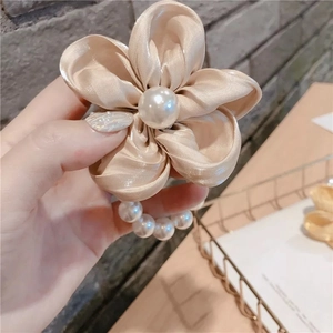 Détail d'élastique à cheveux en satin champagne avec perle et bande de perles tressées