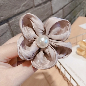 Détail d'un chouchou fleur en satin champagne avec un ornement en perle blanche