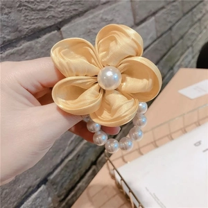 Détail de l'élastique à cheveux fleur en tissu champagne avec perle centrale et perles