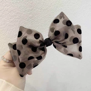 Detailed view of polka dot mesh bow hair clip in taupe with black flocked accents