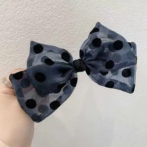 Detailed view of oversized navy blue sheer mesh bow with black flocked polka dots