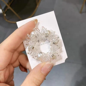 Dettaglio dell'elastico a spirale con perle e resina trasparente su supporto in cartoncino
