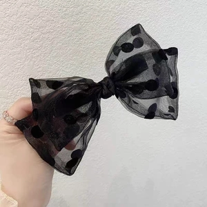 Close-up of oversized black polka dot mesh bow hair accessory with sheer layered fabric