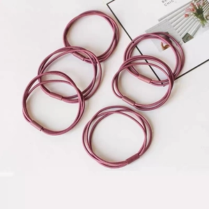 Detail view of pink elastic hair bands with matte cylindrical fastener in a flat lay set
