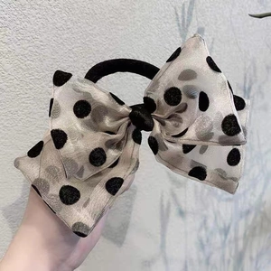 Detail of sheer gold organza bow hair tie with vintage black polka dots texture