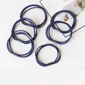 Detail of six navy blue elastic hair ties with black connectors on white background