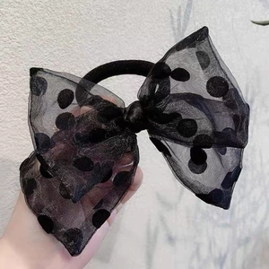 Detailed view of black polka dot bow hair tie made of sheer organza and elastic band