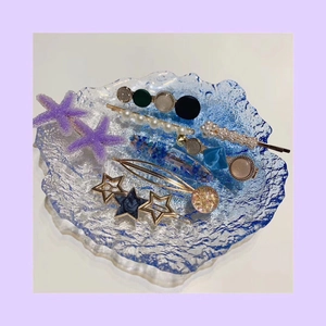 Ocean series hair clip set with pearls and starfish designs on a blue glass plate
