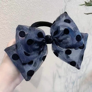 Detail of large mesh bow hair tie with velvet polka dots held by hand for size