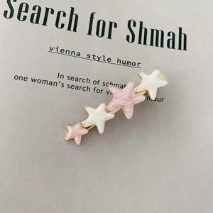 Close-up of cream and pink enamel star hair clips with gold metal base for women
