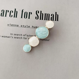 Close-up of cream and blue enamel star hairpins with marble texture on metal clips
