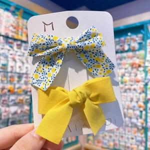 Détail de lot de deux barrettes à nœuds avec motifs floraux jaunes et tissus bleus unis
