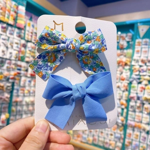 Détail de deux barrettes à nœuds faits main avec motifs floraux et tissus bleus