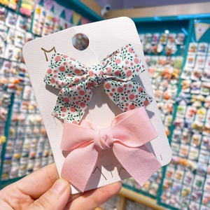 Détail de barrettes à nœuds en tissu rose et floral sur carte de présentation