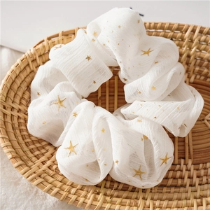 Close-up of white chiffon hair scrunchie with gold stars in a woven basket