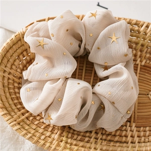 Detail of sweet cream chiffon scrunchie with golden stars pattern in a woven basket