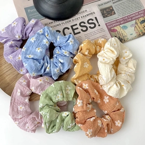 Set of 7 colorful floral scrunchies with daisy patterns on vintage background setup