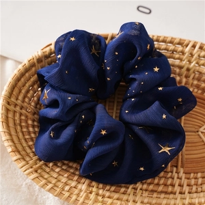 Close-up of deep blue mesh scrunchie with gold star patterns on a woven background