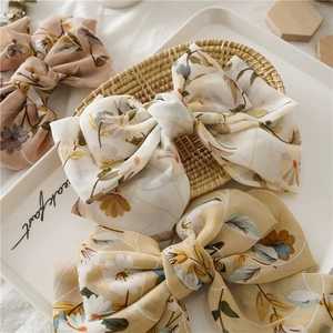 Barrettes à cheveux à fleurs avec nœuds en rose, beige et jaune sur un plateau blanc