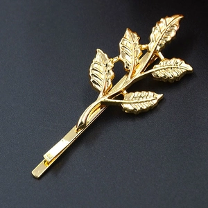 Eleganter goldener Haarclip in Blattform mit feinen Adern auf dunklem Hintergrund